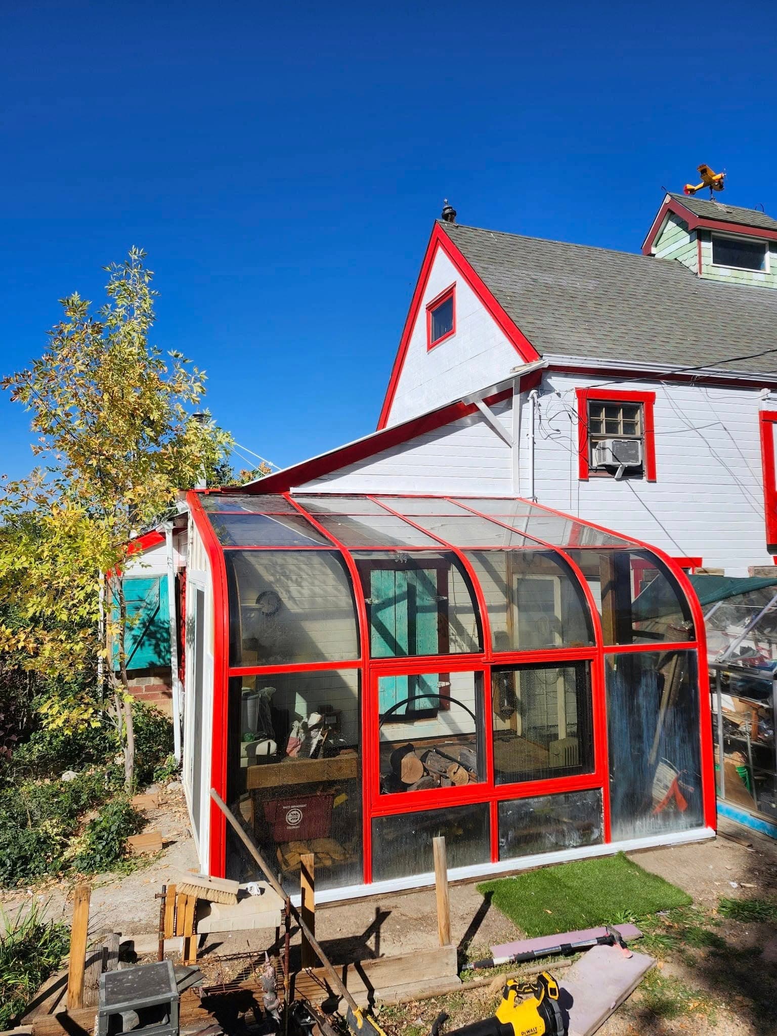 Sunroom enclosure with red-framed glass on house