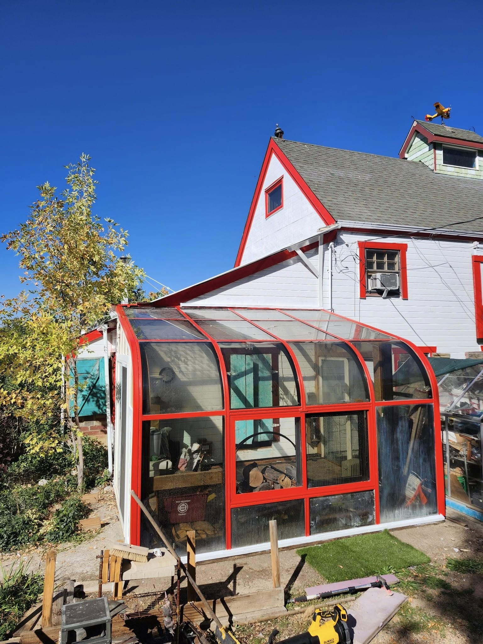 Sunroom enclosure with red-framed glass on house