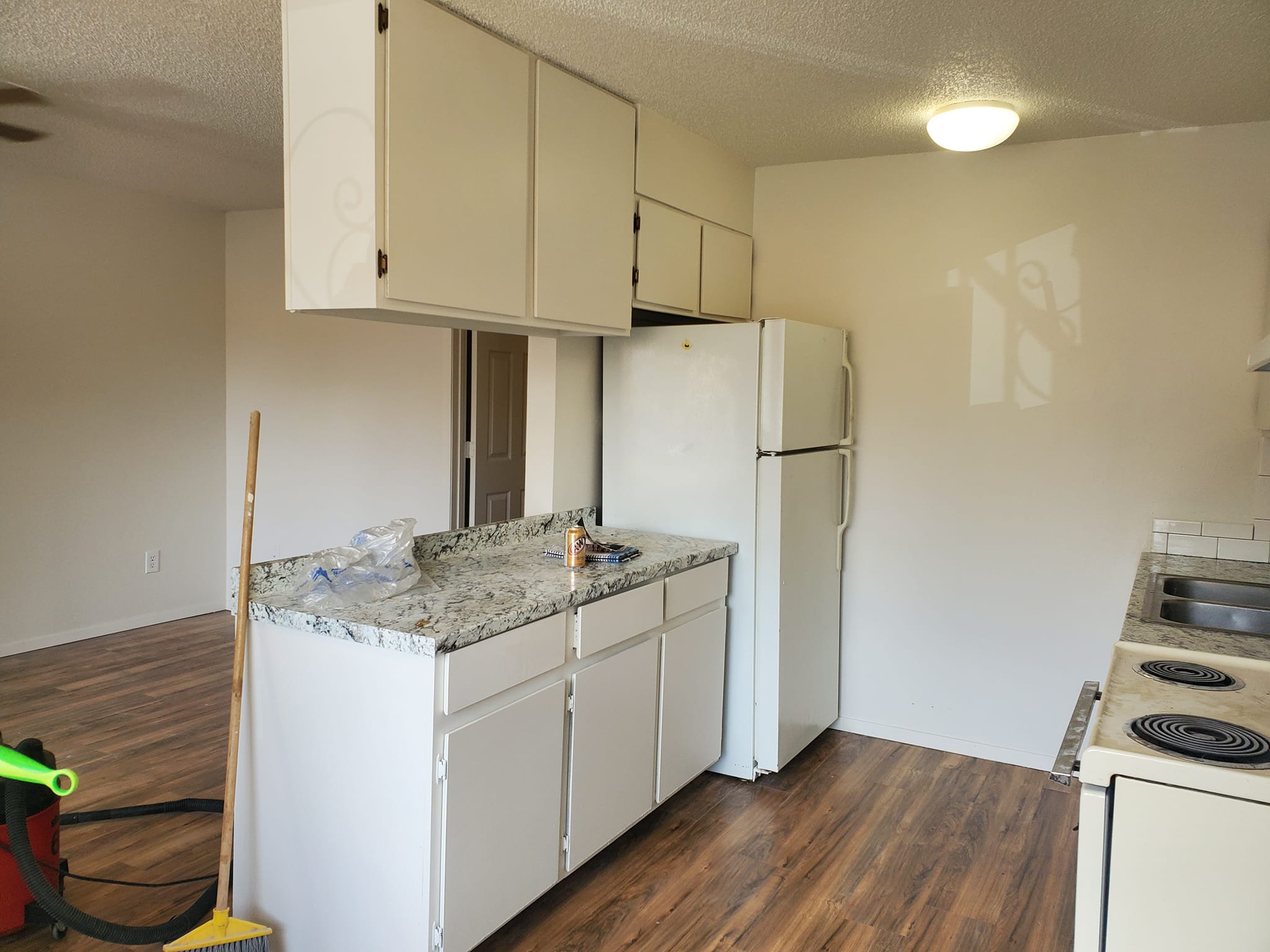 Kitchen renovation in progress with white cabinetry and granite countertops